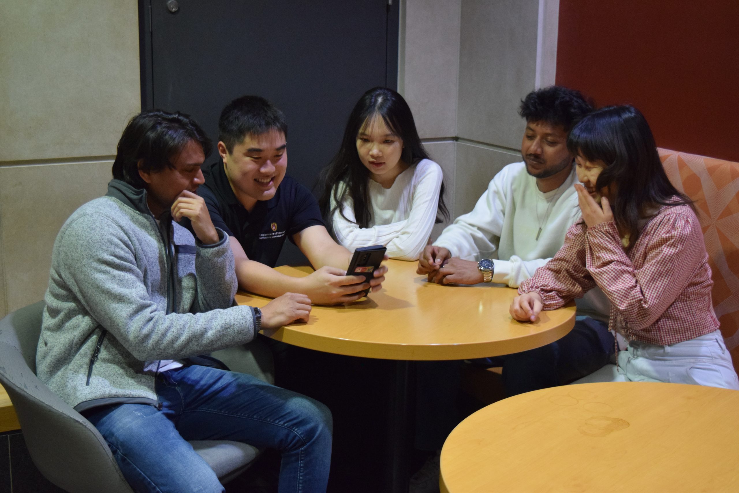 Students are gathered at a table laughing with one another